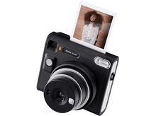 Charger l&#39;image dans la galerie, Appareil photo instantané noir avec photo qui sort. Une femme est sur la photo, fond mur en briques.
