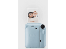 Charger l&#39;image dans la galerie, Un appareil photo Instax bleu clair avec une impression photo qui sort, montrant deux femmes souriantes.
