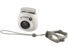 Charger l&#39;image dans la galerie, Appareil photo Instax blanc avec objectif et lanière, tenu par une poignée grise. L&#39;appareil photo est blanc.
