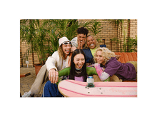 Charger l&#39;image dans la galerie, Cinq personnes diverses riant ensemble, assises sur un canapé, avec un skateboard et un petit haut-parleur.
