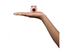 Charger l&#39;image dans la galerie, Main tenant un appareil photo Instax rose. Fond blanc. L&#39;appareil photo a un objectif.
