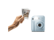 Charger l&#39;image dans la galerie, Une main tenant des photos Instax à côté d&#39;un appareil photo Instax bleu clair.
