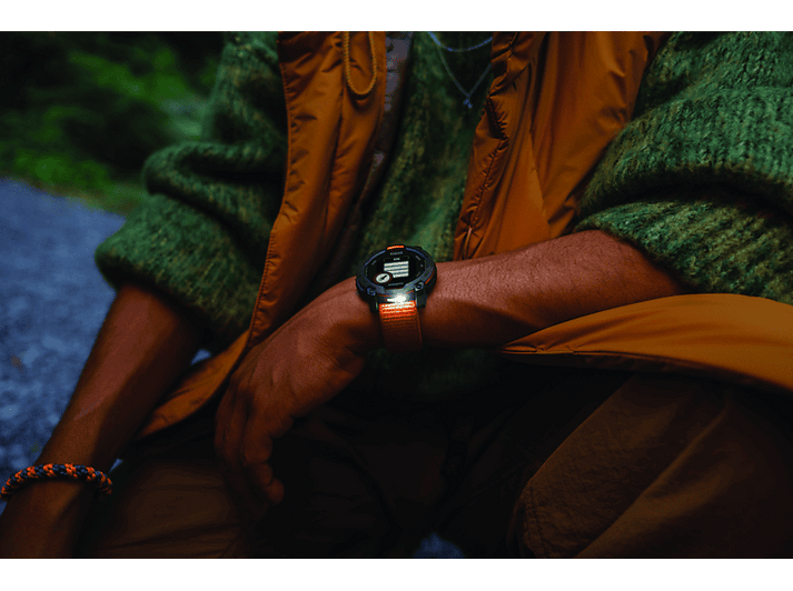 Personne portant une smartwatch, affichant l'heure, devant un fond vert flou.