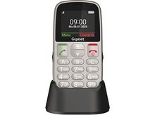 Charger l&#39;image dans la galerie, Un téléphone Gigaset argenté sur une base de chargement noire. Il affiche l&#39;heure, la date et possède des boutons pour les contacts, le menu et les chiffres.
