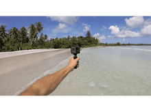 Charger l&#39;image dans la galerie, Une personne tenant une caméra GoPro sur un bâton, capturant une scène de plage avec de l&#39;eau claire.
