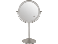 Miroir rond argenté avec une lumière. Le miroir est sur un pied. Le fond est noir.