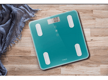 Charger l&#39;image dans la galerie, Balance numérique de couleur sarcelle avec marques de pieds et fond en bois.
