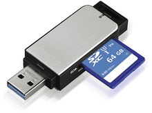 Charger l&#39;image dans la galerie, Lecteur de carte USB argenté et noir avec une carte SD bleue insérée. La carte SD a 64 Go et R85 Mo/s.
