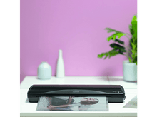 Charger l&#39;image dans la galerie, Une plastifieuse noire avec une photo, un mur rose et une plante verte.
