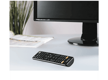 Charger l&#39;image dans la galerie, Une télécommande sur une table à côté d&#39;un moniteur et d&#39;un livre.
