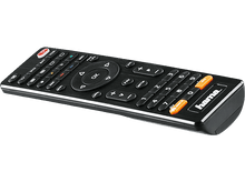 Charger l&#39;image dans la galerie, Une télécommande noire sur une table avec un moniteur et un magazine en arrière-plan.
