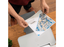 Charger l&#39;image dans la galerie, Une personne tient un document au-dessus d&#39;une imprimante. Le document a un graphique d&#39;une ville.
