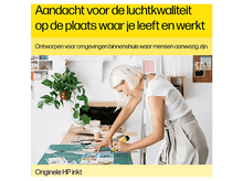 Charger l&#39;image dans la galerie, Une femme coupe du papier sur une table, avec du texte en néerlandais. Une plante est suspendue en arrière-plan.
