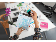 Charger l&#39;image dans la galerie, Personne tenant une cartouche d&#39;encre HP noire et verte dans une enveloppe.
