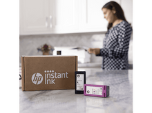 Charger l&#39;image dans la galerie, Femme près d&#39;un comptoir en marbre avec des cartouches d&#39;encre instantanée HP et une boîte d&#39;encre instantanée HP.
