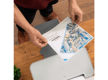 Charger l&#39;image dans la galerie, Une personne tenant un document avec du texte imprimé et une imprimante sur une table en bois.
