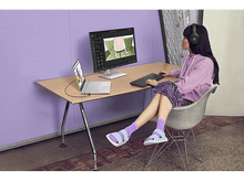 Charger l&#39;image dans la galerie, Femme avec un casque utilisant un ordinateur portable et un moniteur sur un bureau. Le logiciel d&#39;édition est à l&#39;écran.
