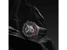 Charger l&#39;image dans la galerie, Une montre connectée noire et grise avec un affichage de carte du monde reposant sur une surface rocheuse sombre et texturée.
