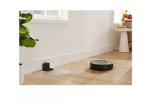 Charger l&#39;image dans la galerie, Aspirateur robot noir et gris sur un sol en bois.
