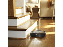 Charger l&#39;image dans la galerie, Aspirateur robot sur plancher en bois près d&#39;un escalier, éclairage vif.
