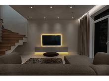 Charger l&#39;image dans la galerie, Salon moderne la nuit. Une TV allumée, un canapé, un tapis et un escalier sont présents. Éclairage doux partout.
