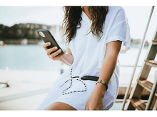 Charger l&#39;image dans la galerie, Une femme tenant un smartphone et le regardant.
