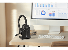 Charger l&#39;image dans la galerie, Casque sur une station de charge, avec un écran d&#39;ordinateur et un clavier. Scène de bureau.

