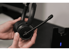 Charger l&#39;image dans la galerie, Une personne tenant un casque noir avec un microphone et une station de charge.
