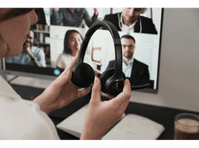 Charger l&#39;image dans la galerie, Personne tenant un casque noir devant un appel vidéo sur un écran d&#39;ordinateur. Le casque est noir.
