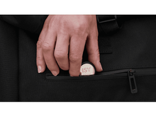 Charger l'image dans la galerie, Main insérant une pièce dans une poche d'un sac noir.
