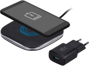 Chargeur sans fil avec un téléphone dessus et un adaptateur secteur. Chargeur et téléphone noirs.