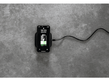 Charger l'image dans la galerie, Téléphone noir se chargeant sur chargeur sans fil noir. Batterie en charge. Surface grise.
