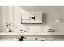 Charger l&#39;image dans la galerie, Un téléviseur monté sur un mur blanc avec une étagère, une table et une suspension.
