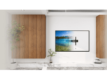 Charger l&#39;image dans la galerie, Salon avec des meubles en bois, une télévision affichant un paysage et une petite plante.
