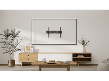 Charger l&#39;image dans la galerie, Une télévision murale. Un meuble en bois se trouve en dessous, avec une plante et des fleurs de chaque côté de la télévision.
