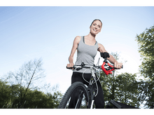 Charger l'image dans la galerie, Femme à vélo, regardant la caméra, soleil.
