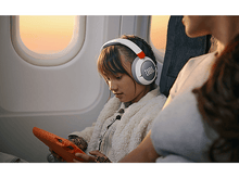 Charger l&#39;image dans la galerie, Fille portant un casque dans l&#39;avion. Tablette à la main. Coucher de soleil visible par la fenêtre.
