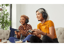 Charger l&#39;image dans la galerie, Deux femmes souriantes avec des casques jouent à un jeu, l&#39;une tenant une manette.
