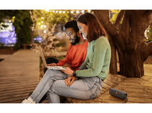 Charger l&#39;image dans la galerie, Un couple assis ensemble avec un ordinateur portable et un haut-parleur.
