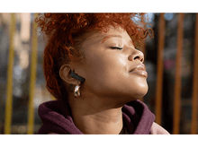 Charger l&#39;image dans la galerie, Femme avec des écouteurs, les yeux fermés, profitant du soleil.
