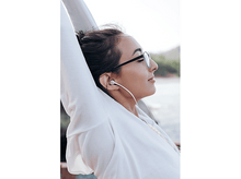 Charger l&#39;image dans la galerie, Femme en lunettes de soleil et sweat à capuche avec écouteurs, regardant en haut.
