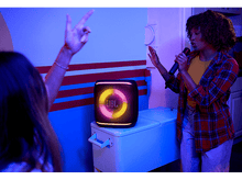 Charger l&#39;image dans la galerie, Femme chantant avec un micro. Enceinte JBL avec lumières colorées sur une glacière.
