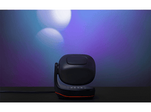 Charger l&#39;image dans la galerie, Un haut-parleur noir sur un support. Le fond est flou avec des teintes bleues et violettes.
