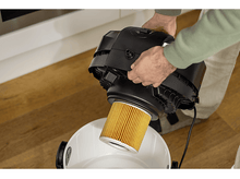 Charger l&#39;image dans la galerie, Une personne retirant un filtre d&#39;un aspirateur noir.
