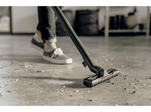 Charger l&#39;image dans la galerie, Personne nettoyant un sol en béton avec un aspirateur.

