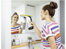 Charger l&#39;image dans la galerie, Une femme nettoyant un miroir avec un appareil de nettoyage qu&#39;elle tient.
