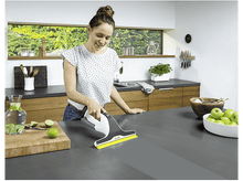 Charger l&#39;image dans la galerie, Femme nettoyant un comptoir avec un nettoyeur de vitres électrique blanc et gris.
