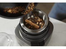 Charger l&#39;image dans la galerie, Une personne verse des épices dans un broyeur en acier inoxydable. Une cannelle est visible.
