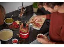 Charger l&#39;image dans la galerie, Un homme en chemise rouge prépare des aliments avec un robot culinaire et des ingrédients.
