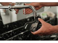 Charger l&#39;image dans la galerie, Une personne utilise un distributeur d&#39;eau pour remplir un appareil noir d&#39;eau.
